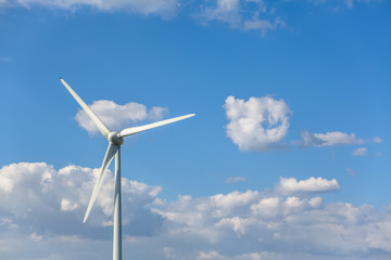 View of a wind turbine on top of mountains, cloudy sky as background