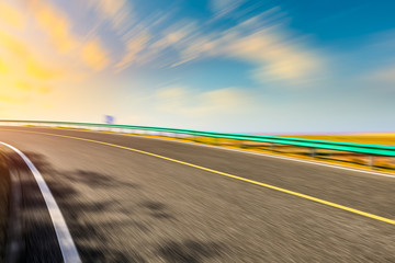 Fototapeta premium Blurred moving asphalt road and colorful sky at sunset