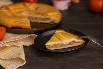 Empanada Gallega, Galician pie, typically filled withtuna  fish  and with red  peppers and tomatos on wooden table. Popular dish in Spanish cuisine.