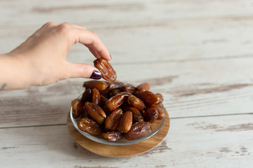 Bowl of dried dates on wooden background with space for text.