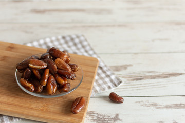 Bowl of dried dates on wooden background with space for text.