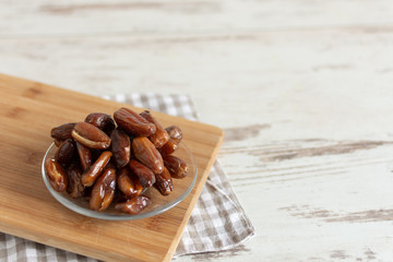 Bowl of dried dates on wooden background with space for text.