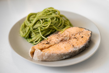 green spaghetti and grilled salmon steak. Top view