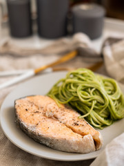 green spaghetti and grilled salmon steak. Top view