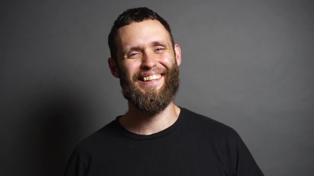 Portrait of a hipster man smiling and having fun. He is over gray background