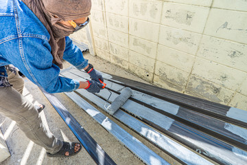 Worker painting steel tube with paint roller