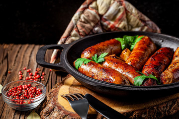 The concept of farm, organic products. Homemade grilled pork barbecue sausages in an iron pan....