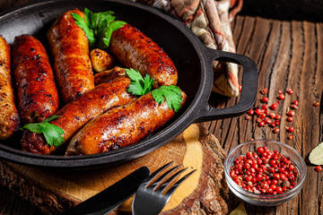 The concept of farm, organic products. Homemade grilled pork barbecue sausages in an iron pan....