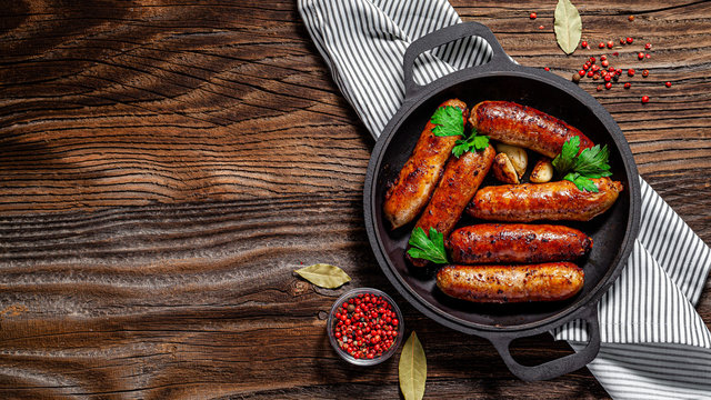 The concept of farm, organic products. Homemade grilled pork barbecue sausages in an iron pan. background image. copy space
