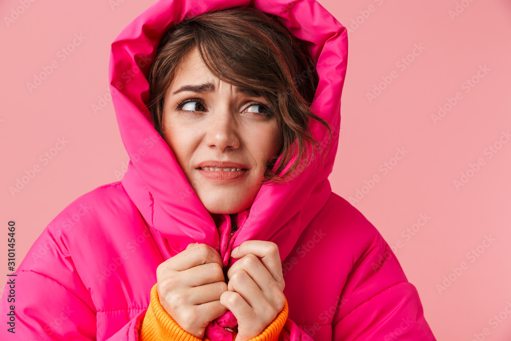 Wall mural portrait of young displeased woman in warm hood is freezing