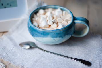 A cup of cacao with marshmellows and christmas decoration on the table with colorful background. Chistmas holiday background. Phantom Blue.