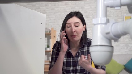 Close up of young woman found leaking under sink and calls plumber
