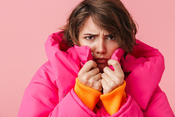 Portrait of displeased young woman is freezing and looking at camera