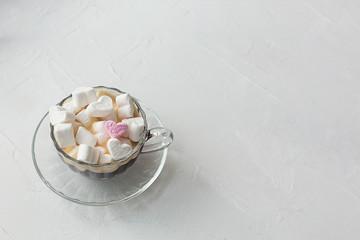 Fototapeta na wymiar Coffee in a cup with saucer and marshmallows hearts on a white textured background. Pink heart.