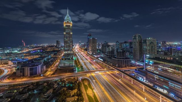 Skyline internet city with crossing Sheikh Zayed Road aerial day to night transition timelapse. Illuminated skyscrapers with traffic on a highway and metro line in Dubai
