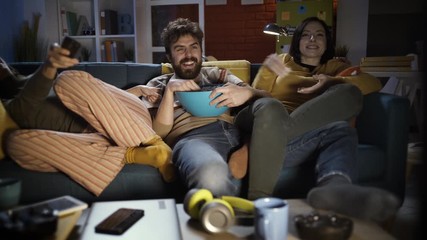 Happy friends watching TV together at home - Powered by Adobe