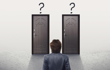 Confused man in suit looking at two similar doors