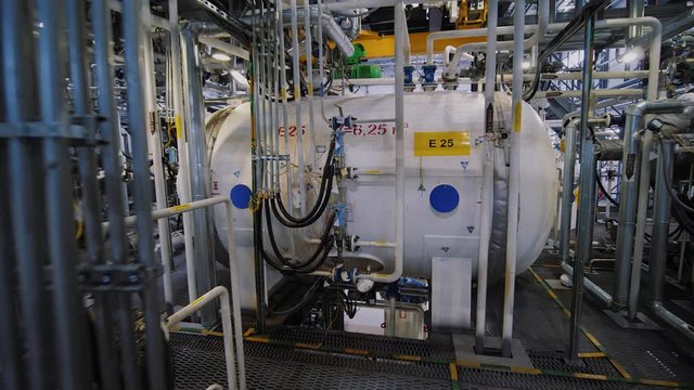 Chemical plant inside. Modern equipment, steel tanks and boilers with cables, pipelines and valves for chemical mixing. Production of anti-turbulent additives used in the oil industry.