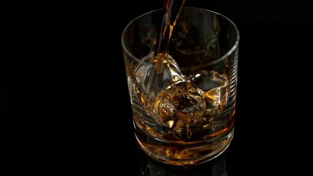 Super Slow Motion Shot of Pouring Whiskey into Glass with Ice Cubes at 1000fps with Camera Movement.