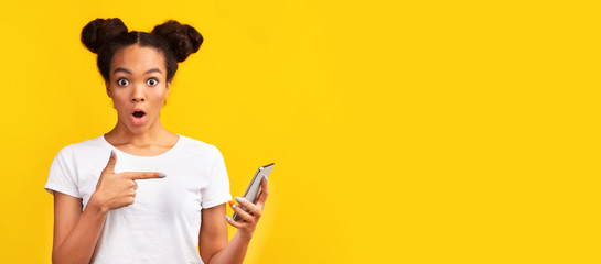 Closeup of amazed black teen pointing at cell phone