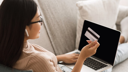 Woman making online purchases with credit card and laptop