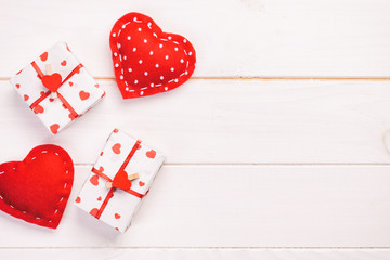 Valentine or other holiday handmade present in paper with red hearts and gifts box in holiday wrapper. Present box gift on white wooden table top view with copy space, empty space for design