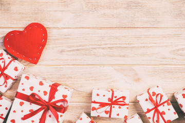 Valentine or other holiday handmade present in paper with red hearts and gifts box in holiday wrapper. Present box of gift on orange wooden table top view with copy space, empty space for design