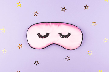 Cute pink sleeping mask on purple background.