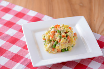 Traditional russian ukrainian salad olivier. Green peas, cucumber, potatoes, meat, mayonnaise.