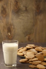 Transparent glass cup with milk and ginger spicy cookies on a wooden table