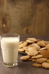 Transparent glass cup with milk and ginger spicy cookies on a wooden table