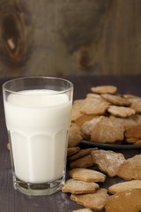 Transparent glass cup with milk and ginger spicy cookies on a wooden table