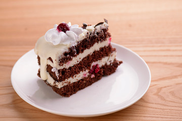 Chocolate vanilla cake with cherry jelly, topped with white cheese frosting and chocolate pieces