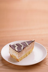 Sweet chocolate spider web cake with frosting on top served on a white plate on light wooden background.