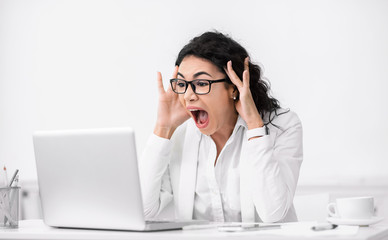 Shocked surprised latin woman using pc and screaming