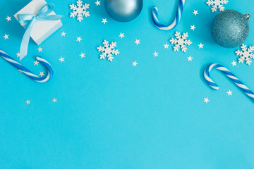 Flat lay Christmas composition. Candy canes and ornaments on blue background