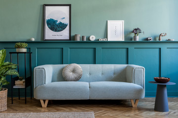 Stylish interior of living room with mint sofa, design furnitures, plants, pillow and elegant accessories. Green wood panelling with shelf. Modern home decor. Mock up poster frame. Template. 