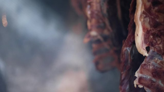 Ham and bacon hanging and drying in smokehouse on traditional way on blue smoke.  The sunrays pierce through the blue smoke.