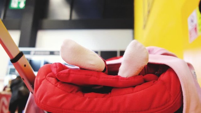 Newborn baby girl swinging her feet while sleeping in a stroller, low angle