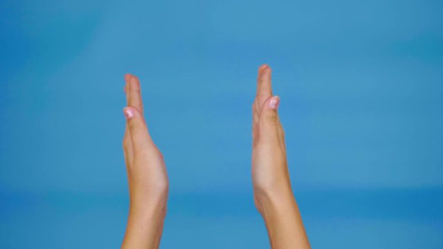 Female hands are clap on a blue background with copy space. Hands of teenage girl. 4k slowmotion footage