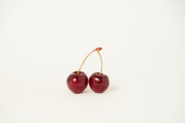 Two isolated raw cherries on a white background with an empty copy space for text, selective focus and toned image