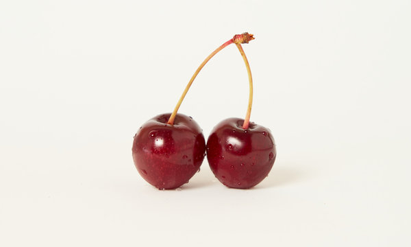 Two isolated raw cherries on a white background with an empty copy space for text, selective focus and toned image
