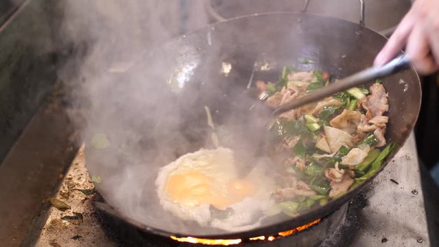 Thai Street food : Chef preparing cooking Thai stir fried noodles with egg, vegetable, pork and soy sauce - Pad See Ew, One of the popular thai dishes, Slow motion 4K, Thai street food.