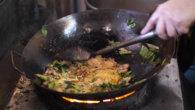 Chef cooking Thai stir fried noodles with egg, vegetable, pork and soy sauce - Pad See Ew, One of the popular thai dishes, Slow motion 4K. Thai street food.