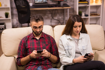 Caucasian couple with serious expressions using their phones