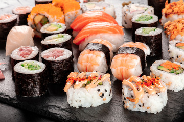 Large sushi set, close-up on a black background. An assortment of various maki, nigiri and rolls