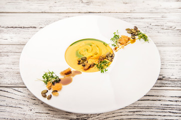 Pumpkin soup puree in a restaurant close-up. Pumpkin puree soup with pumpkin seeds in a plate and copy space.