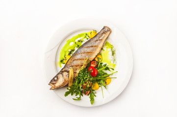 Fish and salad in a restaurant close-up. Dorado on a white plate and copy space.