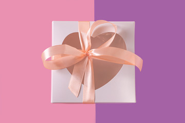 White gift box with heartshaped window on pastel purple background flatlay, creative minimal concept. Transparent heart, pink ribbon bow. Valentines day cards. Top view,copy space,social media banner