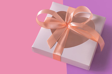 White gift box with heartshaped window on pastel purple background flatlay, creative minimal concept. Transparent heart, pink ribbon bow. Valentines day cards. Top view,copy space,social media banner